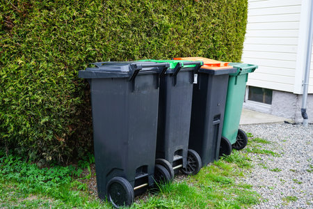 A row of garbage bins with different colored lids for separate waste collection: plastic, paper, glass, organic waste, and general trash. Concept of recycling, sustainability, and eco-friendly waste management.の写真素材