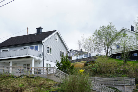 Modern residential houses built on a green hillside, surrounded by trees and shrubs.の写真素材