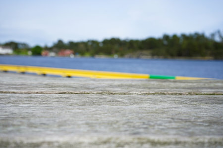 Close-up view of a wooden pier with bright yellow and green railing in front of a calm lake and...