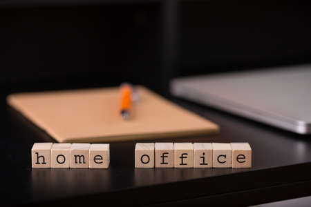 Close up view of a black work desk interior with a laptop computer, a cup of coffee, paper, pen and a cactus with flowers.の写真素材