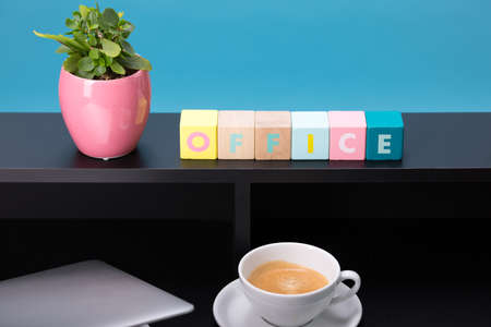 Close up view of a black work desk interior with a laptop computer, a cup of coffee, paper, pen,...
