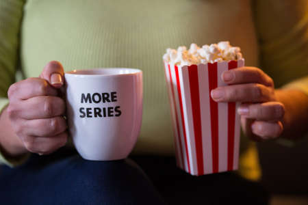 Home Cinema. Watching tv series with a cup of tea that say more series and pop corn