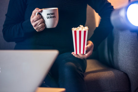 Home Cinema. Watching tv series with a cup of tea that say more series and pop cornの写真素材