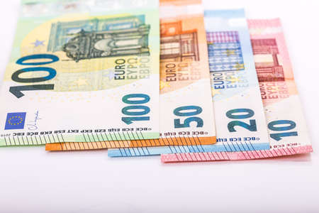 pile of paper and metal euro banknotes and coins on a white background as part of the united...
