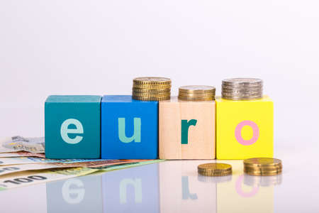 pile of paper and metal euro banknotes and coins on a white background with lettering as part of the united country's payment system. Â© Michele Agostinis / Visualbrand Photographyの写真素材