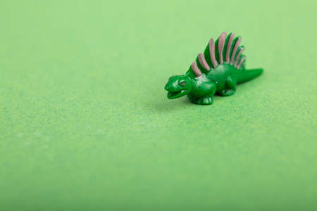 Green background with a Green plastic Dinosaur.