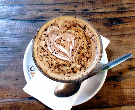 Milk coffee with a heart shape that dots chocolate in a white cupの写真素材