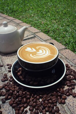 coffee milk with a tree shape in a cup with coffee beans underneathの写真素材