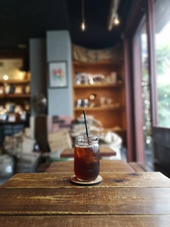 iced tea in a large glass with a straw with a cafe backgroundの写真素材