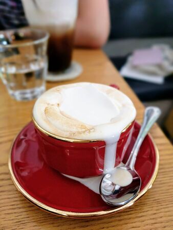 white milk coffee in a red cup on the tableの写真素材