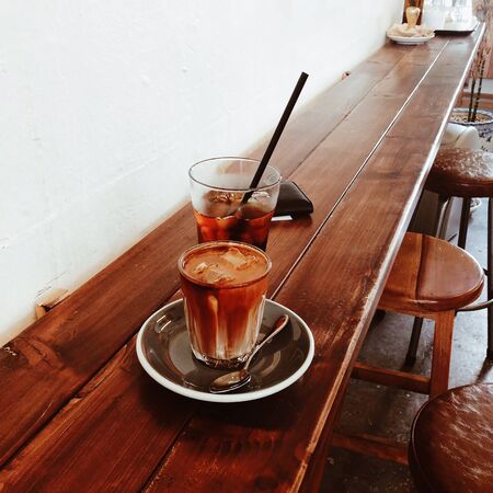 milk coffee with ice in a transparent glass on a wooden tableの写真素材