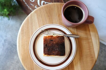 black coffee with snacks on a plate on a wooden tableの写真素材