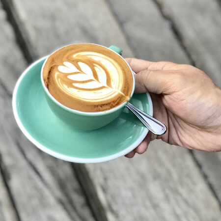 uniquely shaped milk coffee inside a green cupの写真素材
