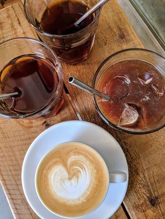 three teas with ice cubes and one milk coffee in a cupの写真素材