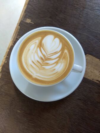 cappuccino in a white cup on a wooden tableの写真素材