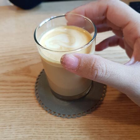 milk coffee in a glass held by handの写真素材