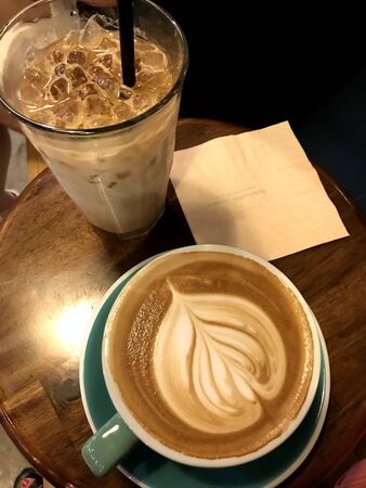 milk coffee with ice cubes on the table and coffee milk in cups on the tableの写真素材
