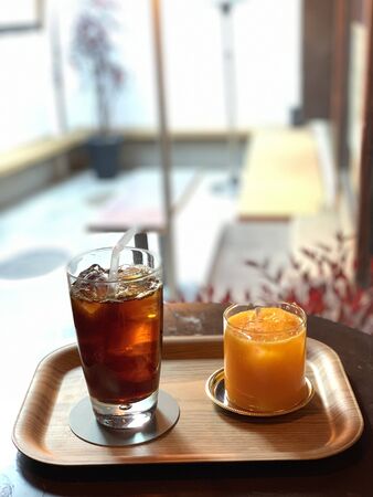ice tea in a glass and orange ice in a glass on a trayの写真素材