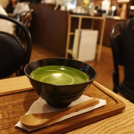 Green tea in a cup on a tray on a wooden table with motion blurの写真素材