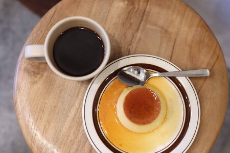 dessert pudding with caramel on a plate with black coffeeの写真素材