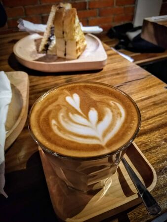heart-shaped milk coffee in a cup with a cafe backgroundの写真素材