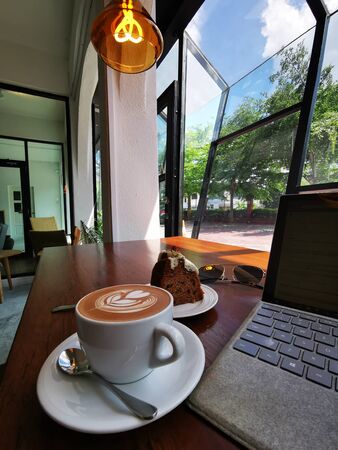 milk coffee with bread snacks and a laptop with a parking lot in the backgroundの写真素材