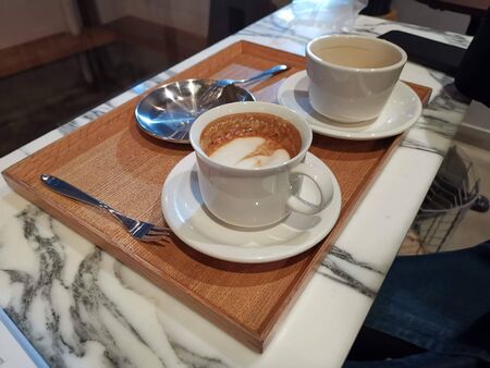 coffee milk in a cup on a wooden trayの写真素材