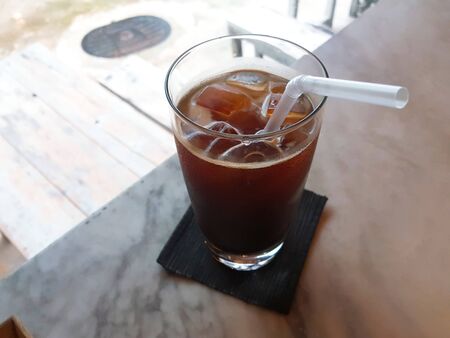 ice tea with ice cubes and a straw in a glass on a white tableの写真素材