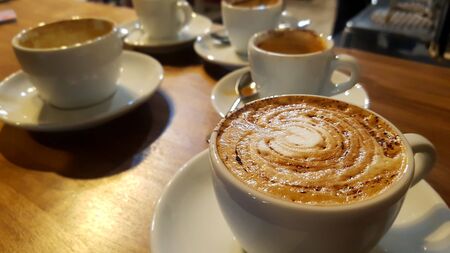 cappuccino with chocolate powder in a cup and a cup with coffee that runs out with motion blurの写真素材