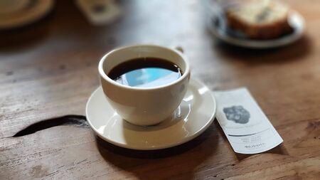 hot tea in a cup on a wooden table with paperの写真素材