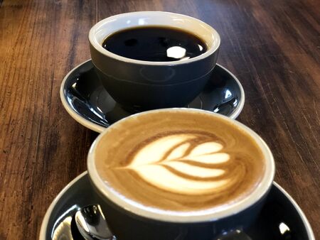 one coffee milk and one black coffee in a cup with motion blurの写真素材