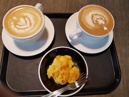 two milk coffees with a unique shape on the spice and snacks on the plateの写真素材