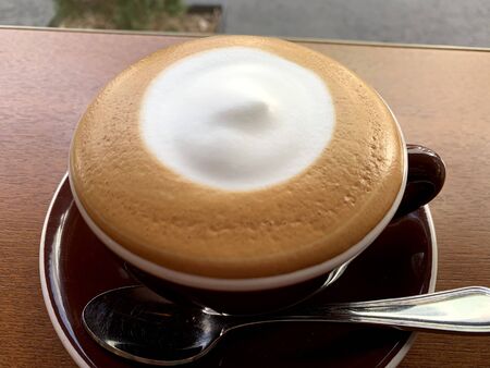 milk coffee with cream in the middle in a white cupの写真素材
