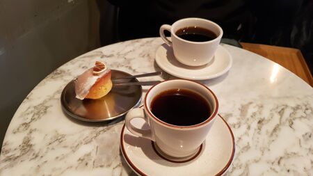 two teas in a cup with a cream sandwich on a plateの写真素材