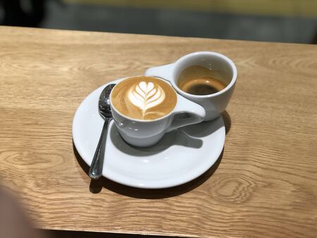 milk coffee in a white cup on a brown wooden tableの写真素材