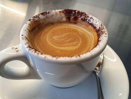 cappuccino with chocolate powder in a white cupの写真素材