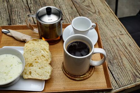 Black coffee in a cup with snacks next to itの写真素材