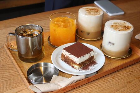 sweet food with cream and chocolate powder with many drinks beside itの写真素材