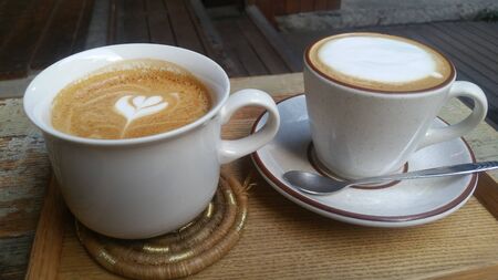 two different types of milk coffee in a white cupの写真素材