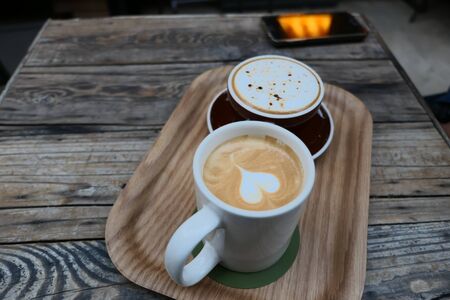 two coffee milk in a tray on a wooden tableの写真素材