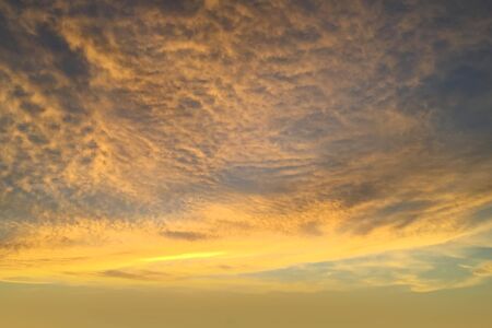 Brilliant yellow sunset and sunrise beautiful over gray clouds with bright yellow sun on a cool spring evening.の写真素材