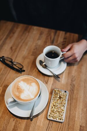 black cup coffee is the place to see various tropical and on brown wooden background.