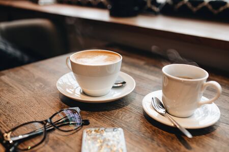 black cup coffee is the place to see various tropical and on brown wooden background.