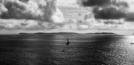 green and sea blue and sky blue beautiful sea and sunset with large yellow sun under the sea surface hills in the background.の写真素材