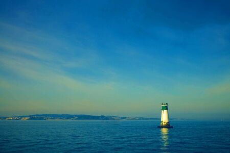 green and sea blue and sky blue beautiful sea and sunset with large yellow sun under the sea surface hills in the background.の写真素材