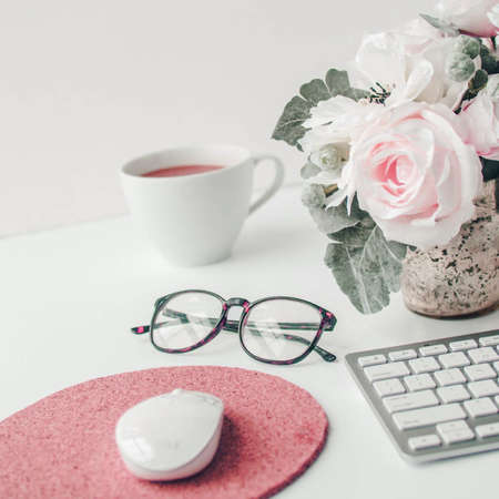 white workspace with light pink note book and white flower with coffee on white table background.の写真素材