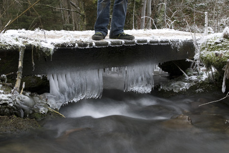icicles hanging on a small bridge crossing a stream in the Belgian Ardennesの写真素材