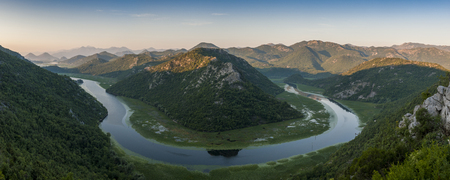 Panoramic aerial view of beautiful green pyramid sheep at the Rijeka Crnojevi river in Montenegro, and its surrounding green mountain range, near its river mouth Skadar Lake.の写真素材