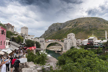View on Stari Most 'old bridge' in Mostar with the Neretva river and tourists walking in the small streetsのeditorial素材