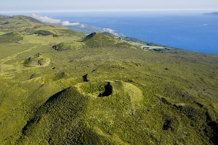 Aerial image of typical green volcanic caldera crater landscape with volcano cones of Planalto da Achada central plateau of Ilha do Pico Island, Azores, Portugalの写真素材